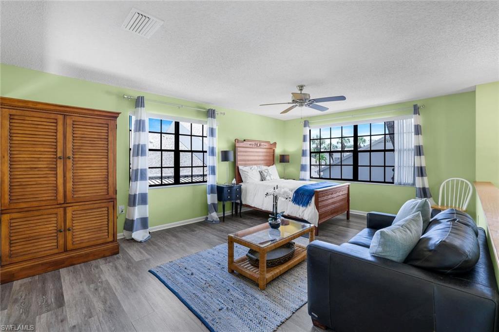 Bedroom with a textured ceiling, wood finished floors, and ceiling fan