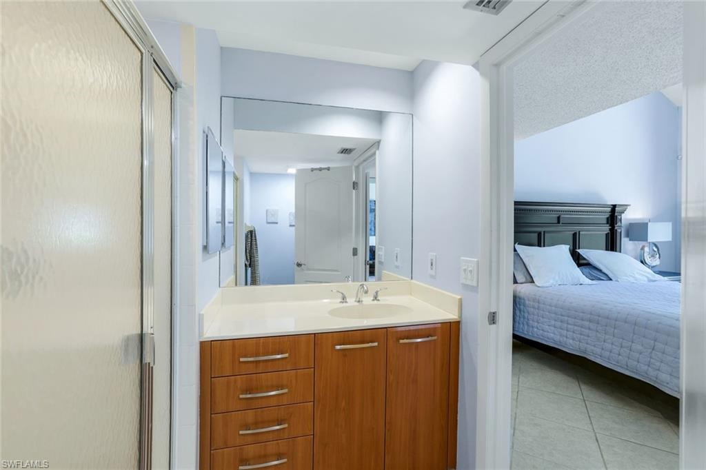 Ensuite bathroom featuring a shower stall, vanity, and light tile patterned floors