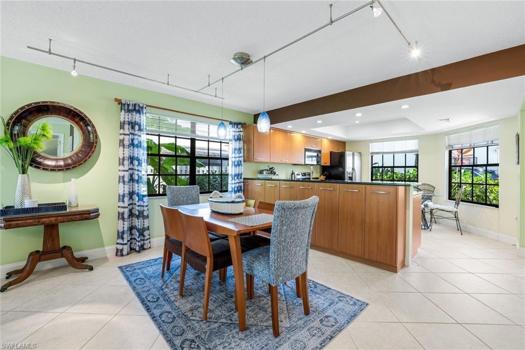 Dining space with rail lighting, plenty of natural light, light tile patterned floors, and recessed lighting