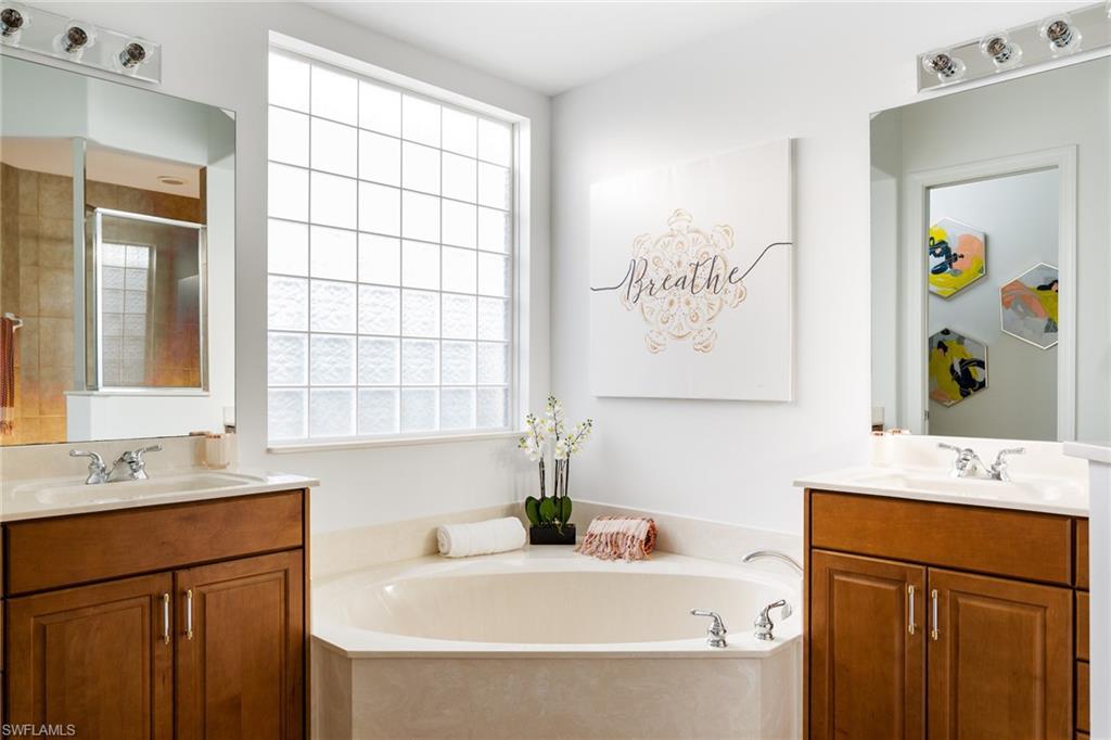 Bathroom featuring a bath, two vanities, and a shower stall