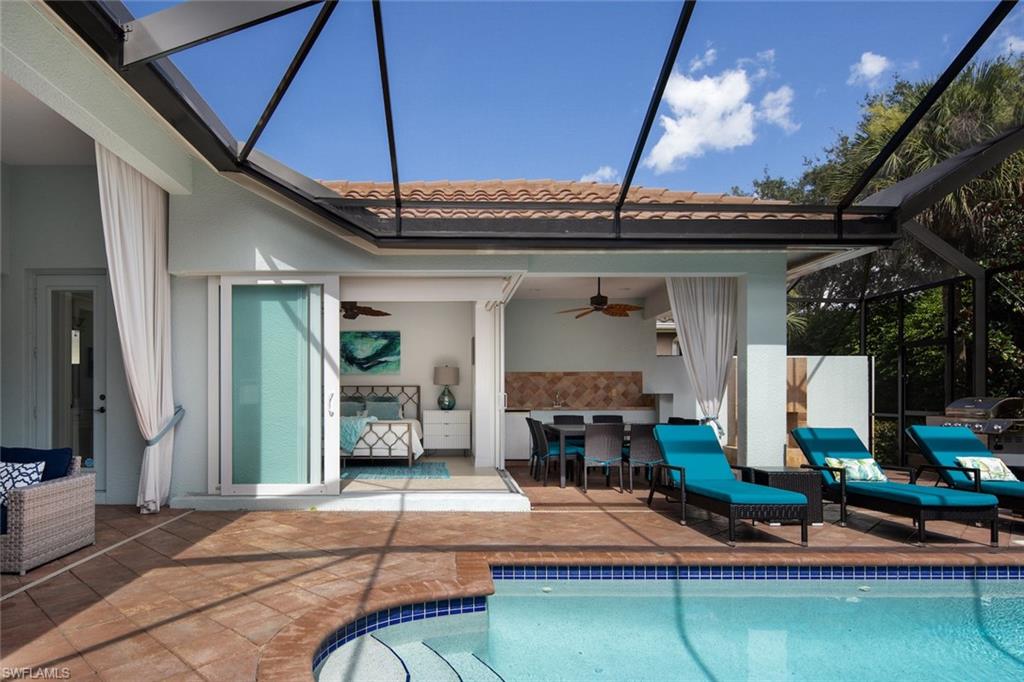 Swimming pool featuring glass enclosure, a sunroom, a patio, and area for grilling