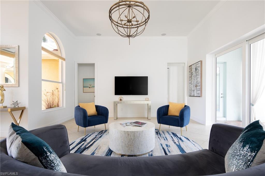 Tiled living area with ornamental molding and a chandelier