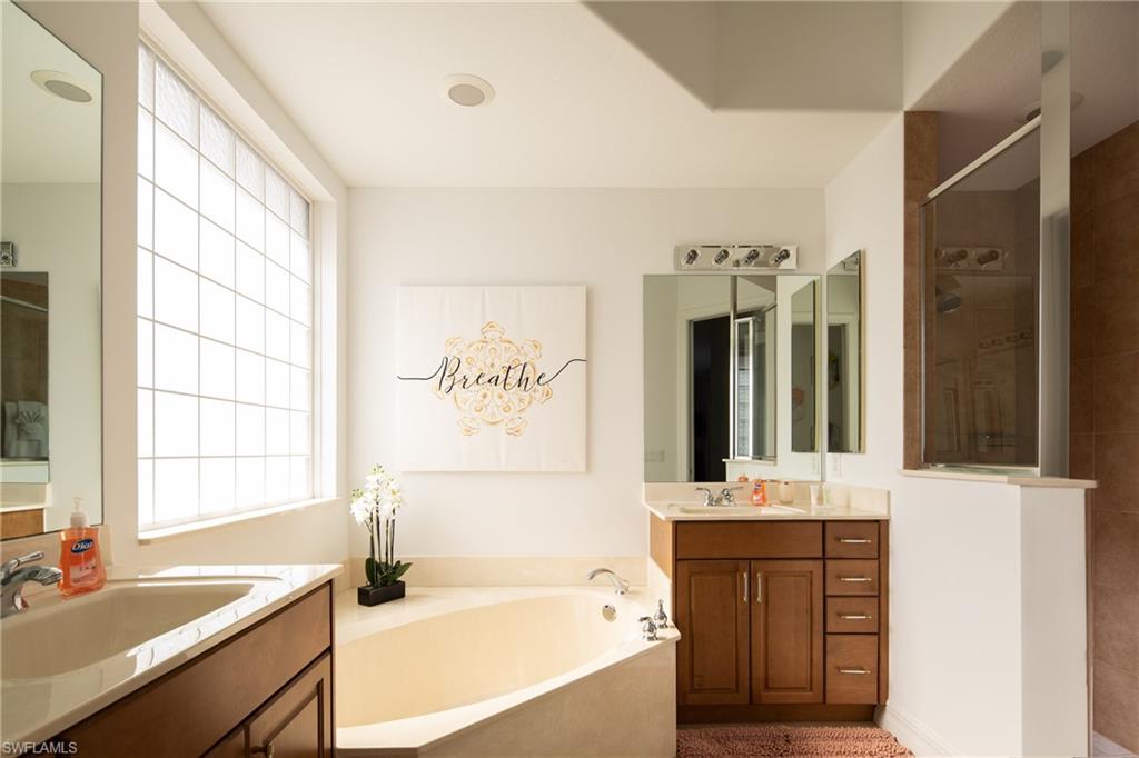 Full bath featuring a stall shower, a garden tub, and two vanities