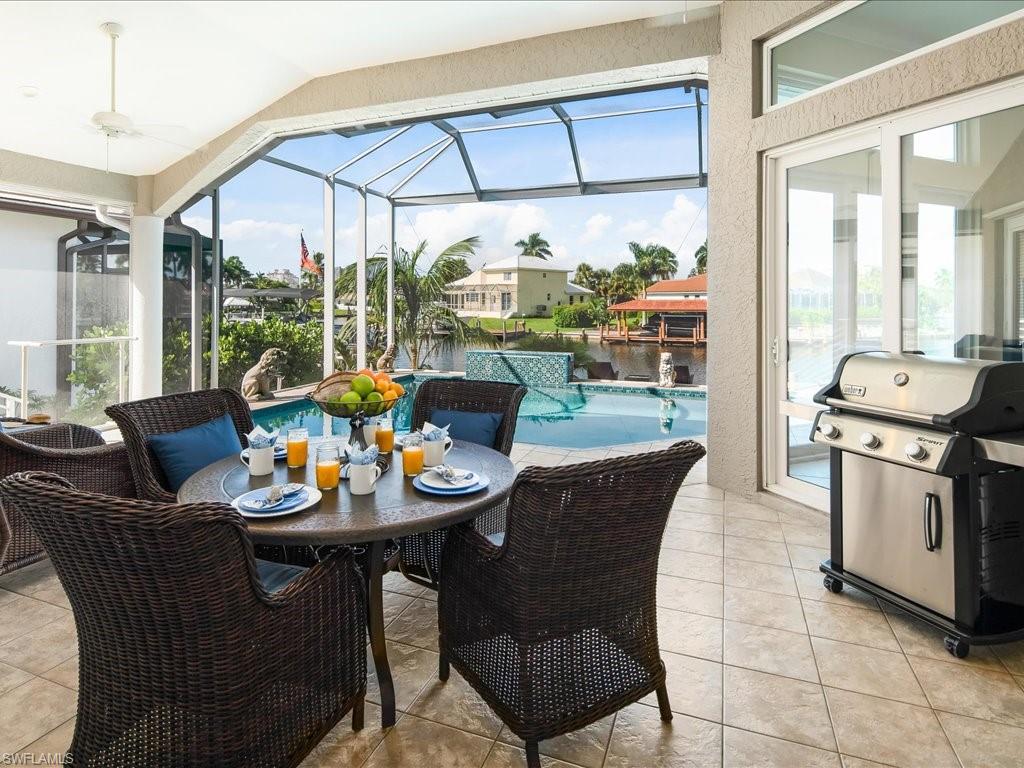 View of patio with an outdoor pool, a water view, a sunroom, grilling area, and glass enclosure