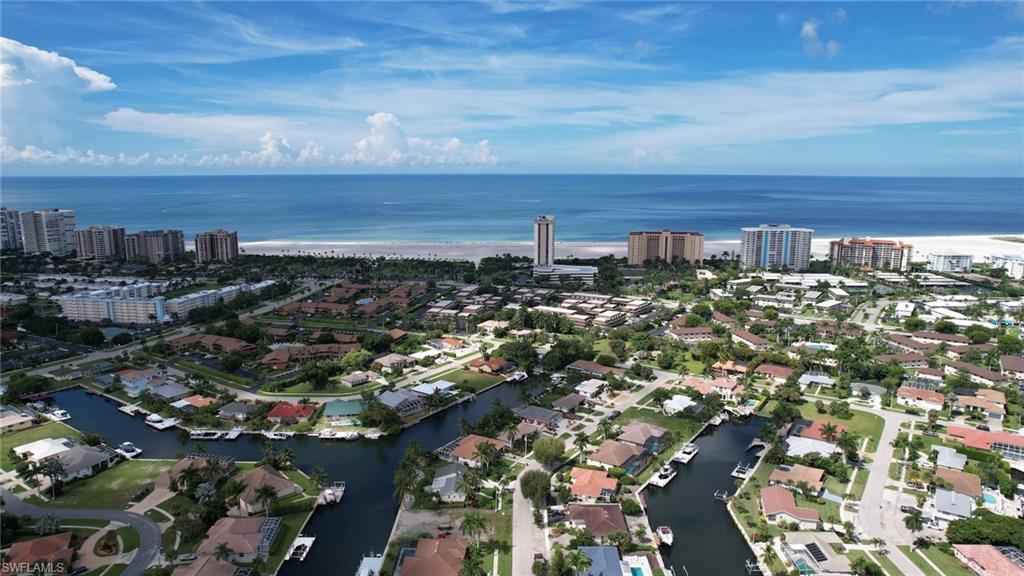 Aerial view of property and surrounding area featuring a nearby body of water and nearby suburban area