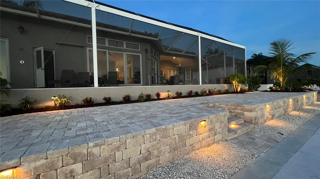Rear view of house with a lanai, stucco siding, a sunroom, and a patio area