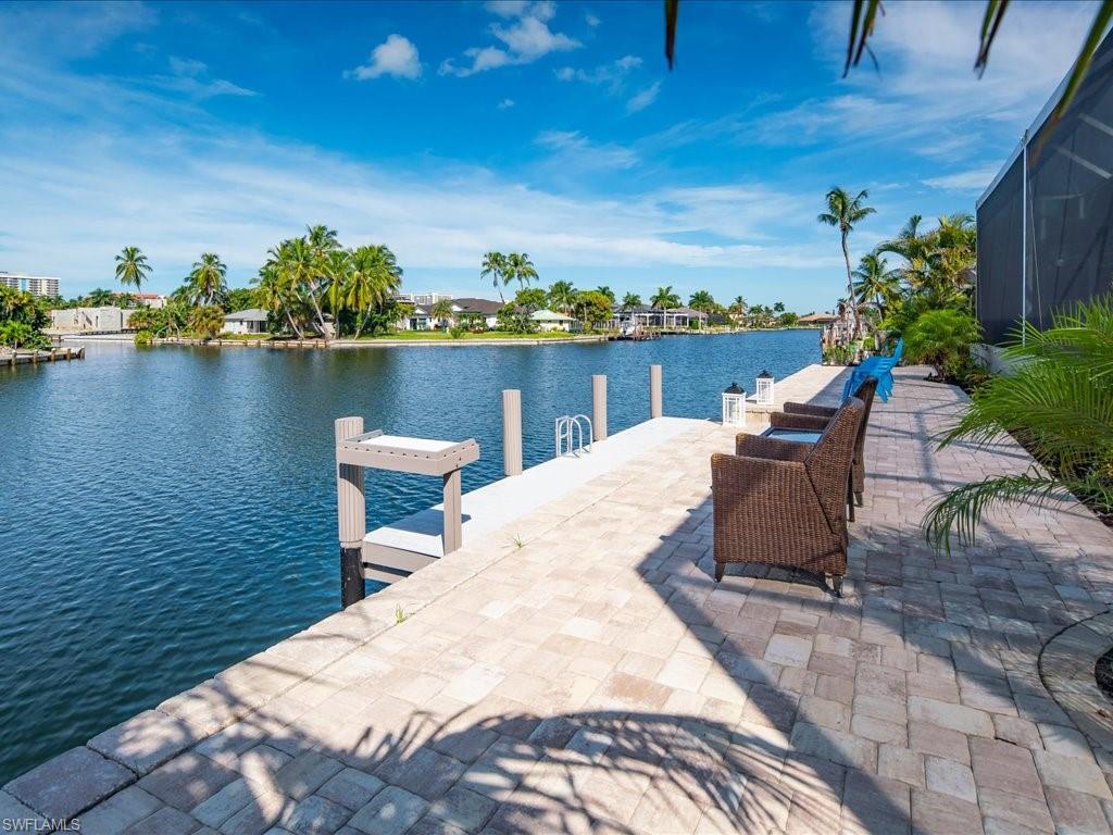 Dock featuring a water view, a patio area, and glass enclosure