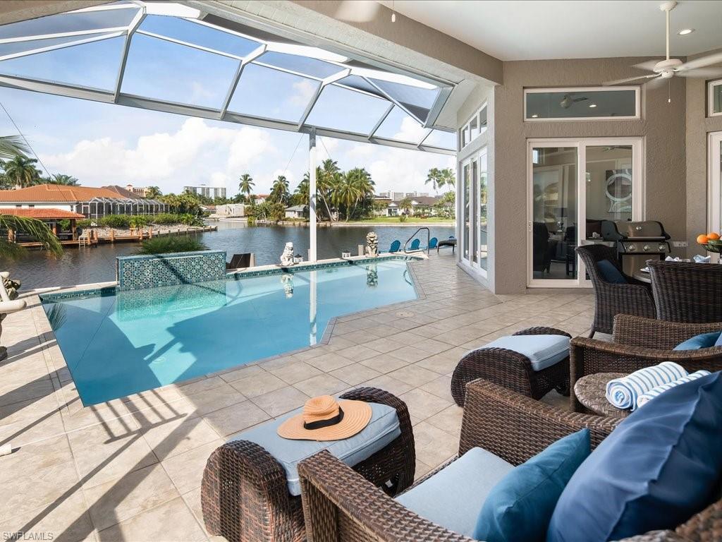 Outdoor pool with a patio, a water view, a sunroom, glass enclosure, and a ceiling fan