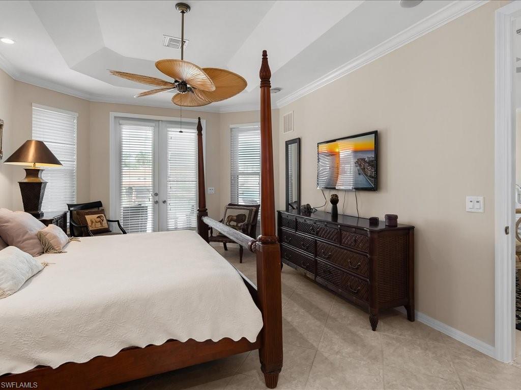 Bedroom featuring a raised ceiling, crown molding, french doors, a ceiling fan, and access to exterior