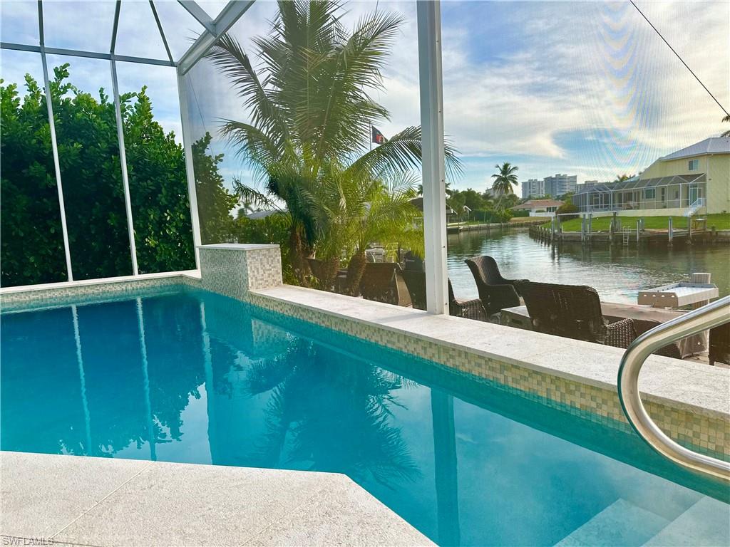 Outdoor pool with a water view, a lanai, and a sunroom