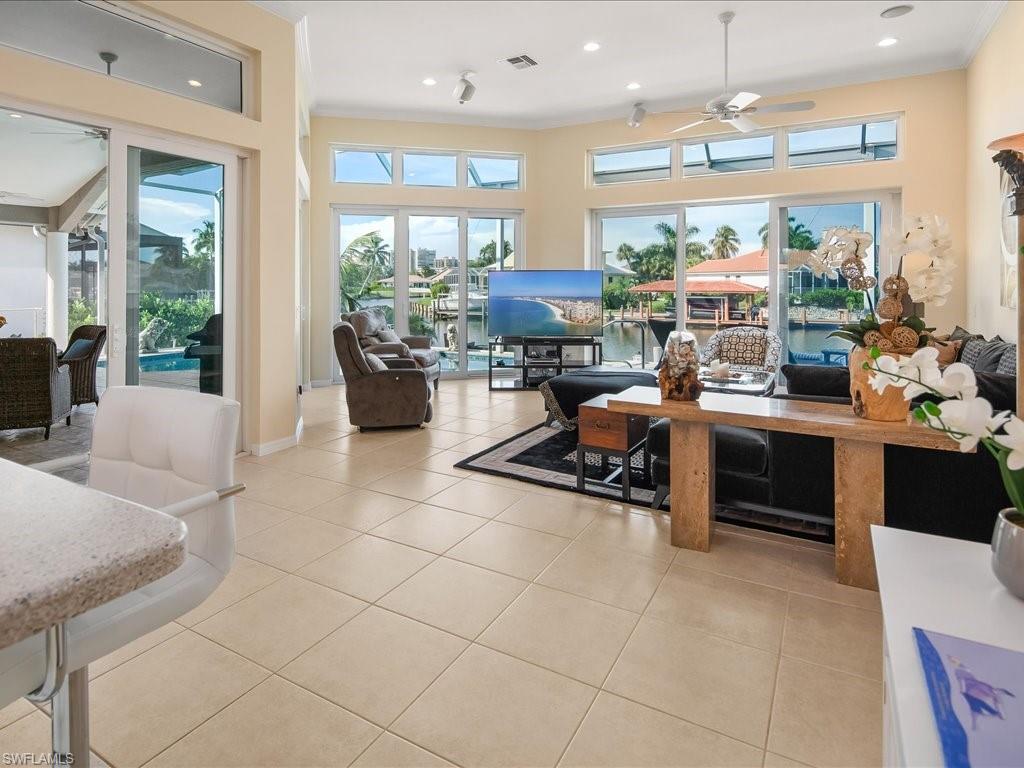 Living room featuring a ceiling fan, light tile patterned floors, plenty of natural light, crown molding, and recessed lighting