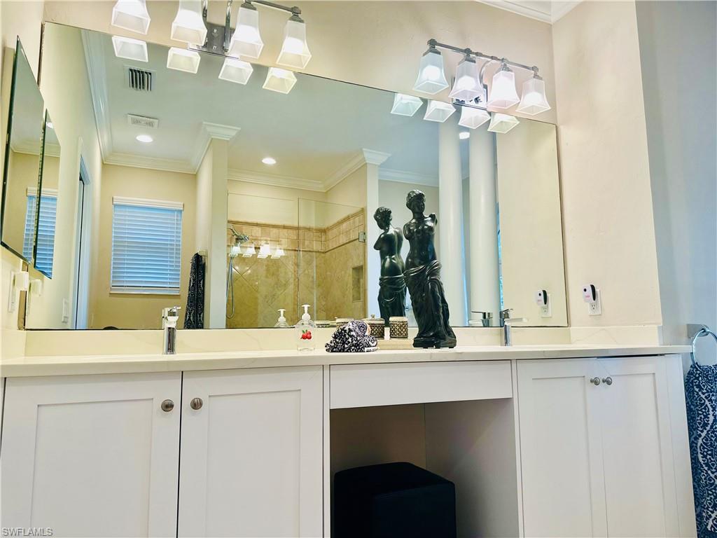 Bathroom with a stall shower, double vanity, and ornamental molding