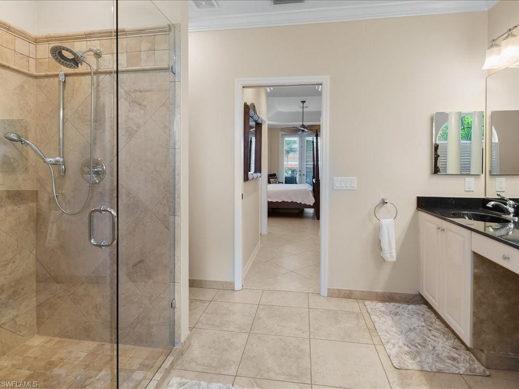 Ensuite bathroom with a stall shower, vanity, crown molding, and light tile patterned floors