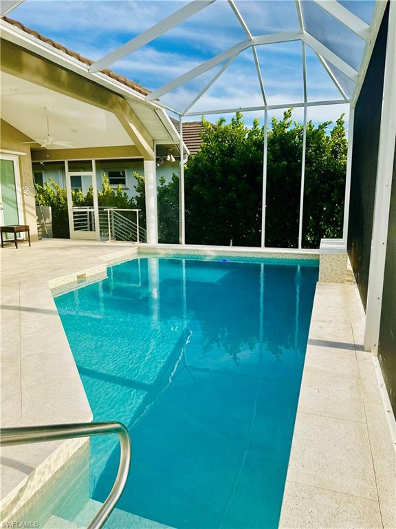 Swimming pool featuring a sunroom, glass enclosure, a ceiling fan, and a patio