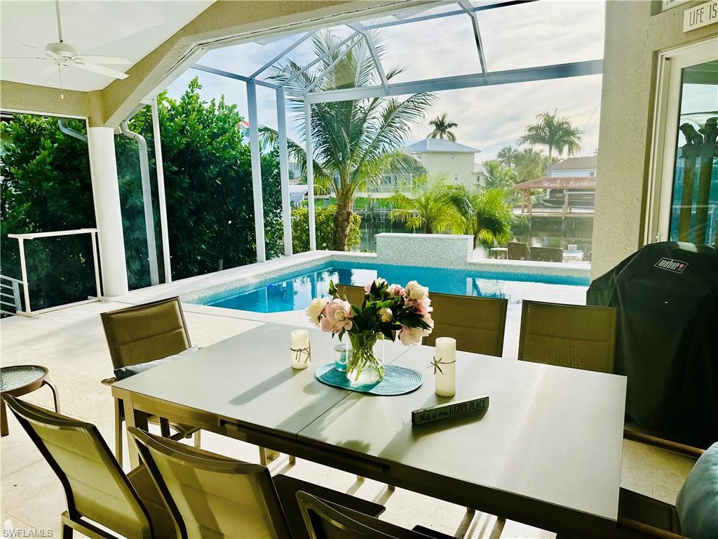 Swimming pool with outdoor dining area, ceiling fan, a grill, and a lanai