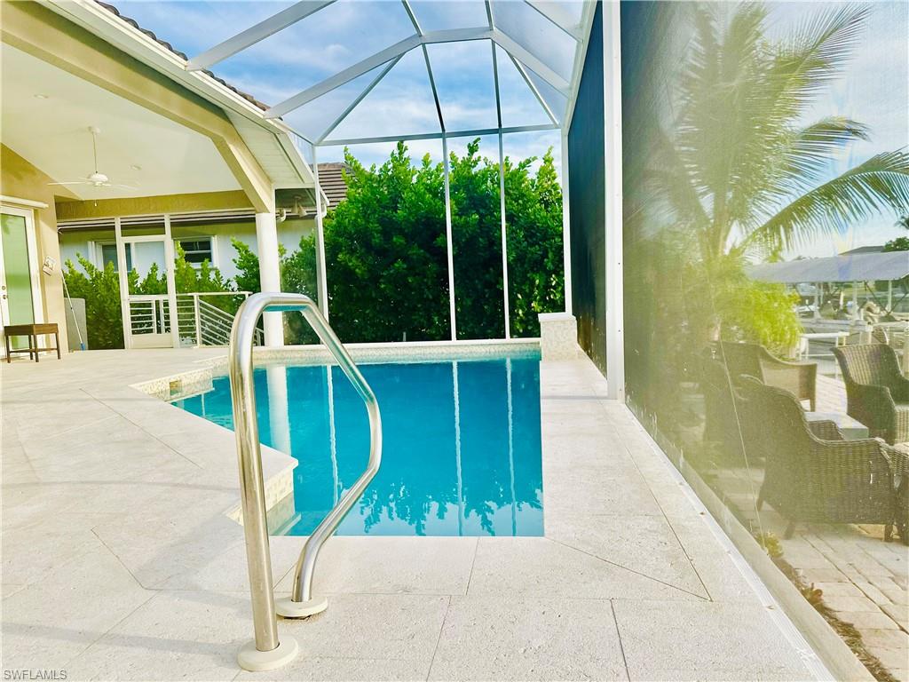 Outdoor pool with a sunroom, a patio area, glass enclosure, and ceiling fan