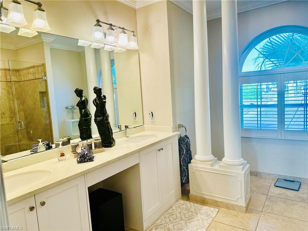 Bathroom with a stall shower, crown molding, double vanity, and light tile patterned flooring