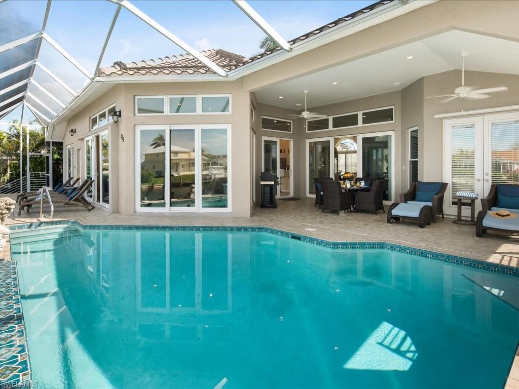 Outdoor pool featuring a sunroom, ceiling fan, a patio area, a lanai, and grilling area