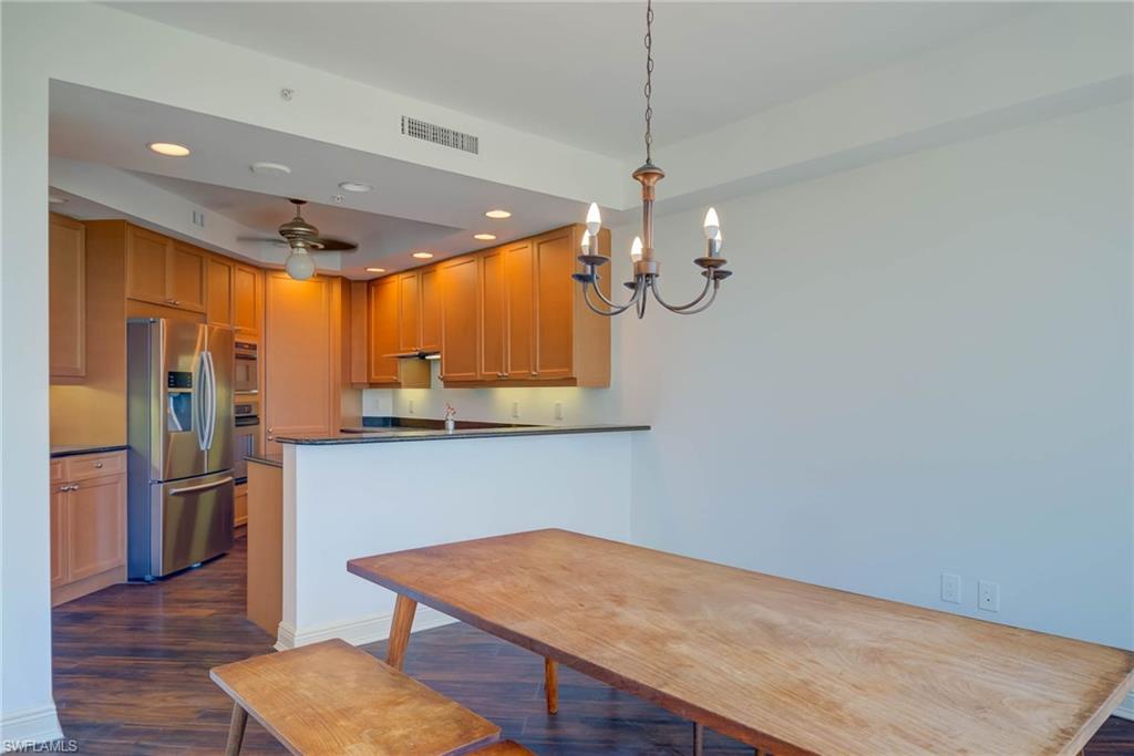Kitchen featuring dark wood-style floors, recessed lighting, stainless steel fridge, a peninsula, and hanging light fixtures