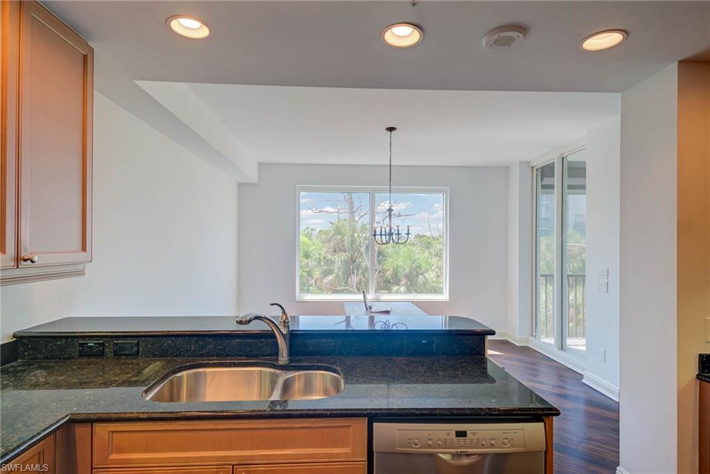 Kitchen featuring recessed lighting, dark stone counters, dishwasher, dark wood-style flooring, and a chandelier