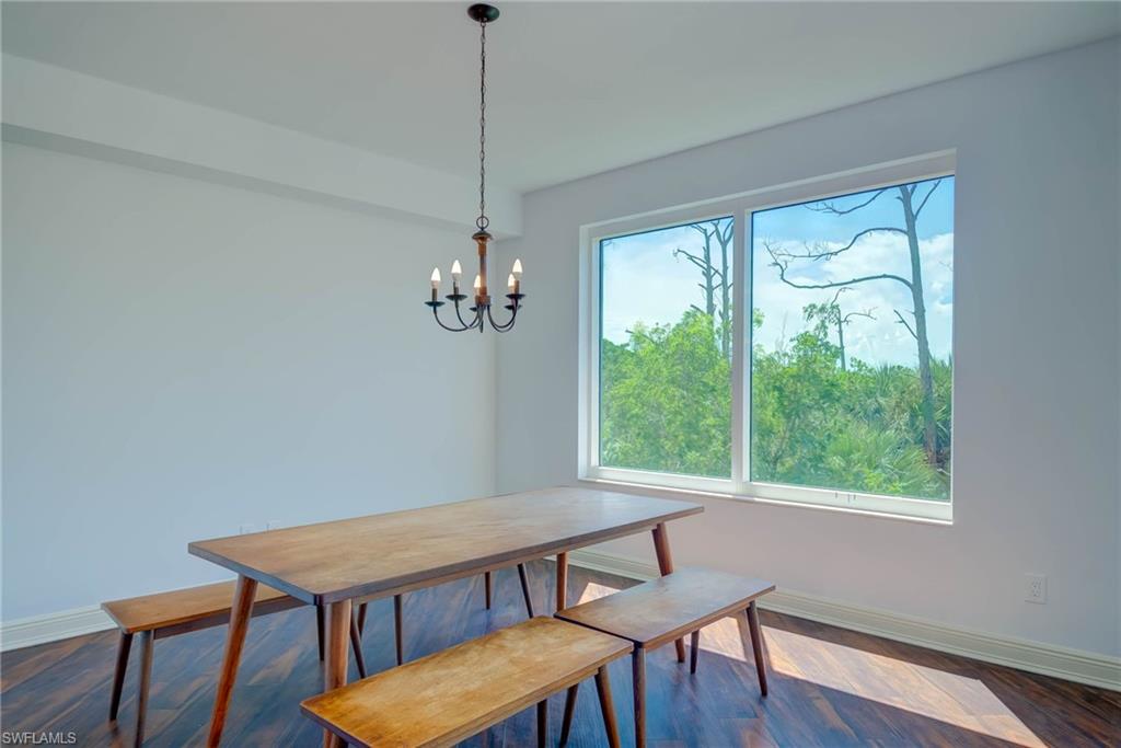 Breakfast Room with dark wood flooring and a chandelier. Entry from Entry and Sliders to Large Back Balcony.