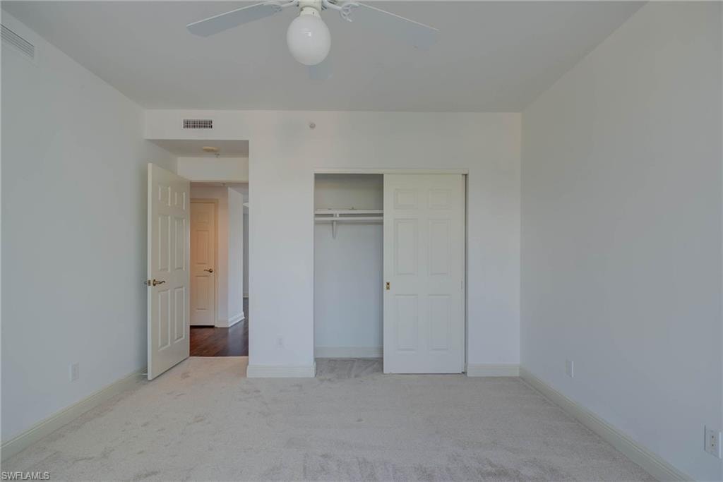 Unfurnished bedroom with carpet floors, a closet, and a ceiling fan