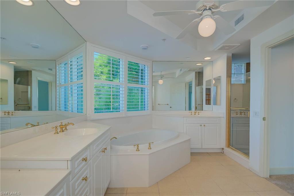 Full Principal bath with two vanities, light tile patterned floors, a garden tub, a stall shower, and recessed lighting