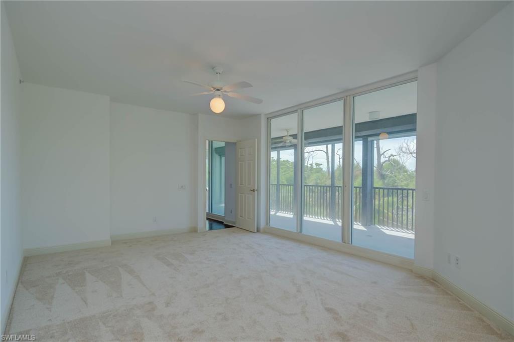 Great room featuring light colored carpet, floor to ceiling windows, and a ceiling fan