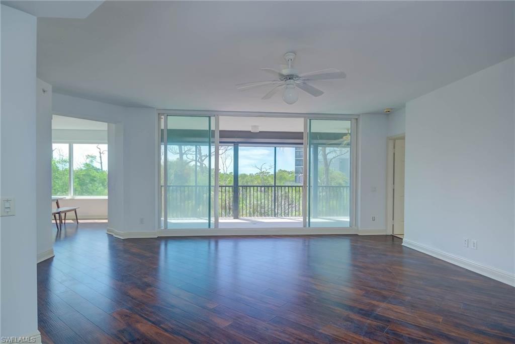 Empty room featuring healthy amount of natural light, dark wood-style flooring, and a ceiling fan
