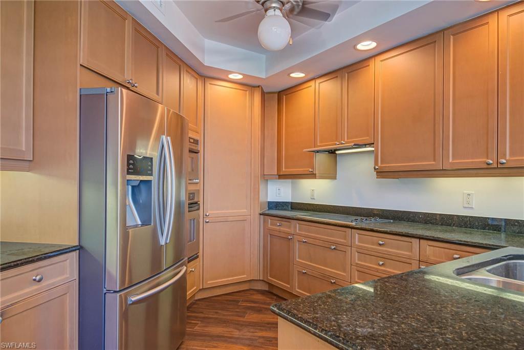 Kitchen with appliances with stainless steel finishes, recessed lighting, dark wood-type flooring, dark stone counters, and a ceiling fan