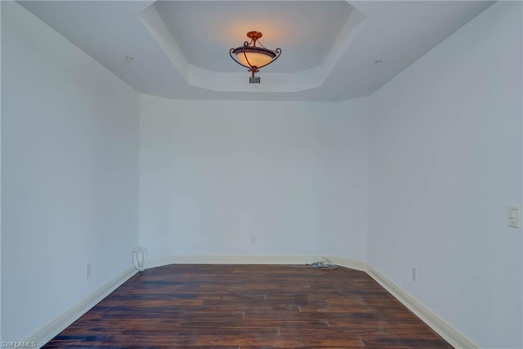 Multi use room with a raised ceiling and dark wood finished floors.  Dining Room, Office, Library, etc..