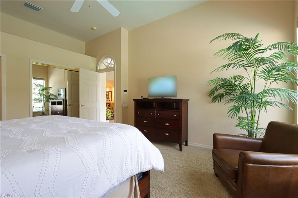 Carpeted bedroom with ceiling fan and a closet