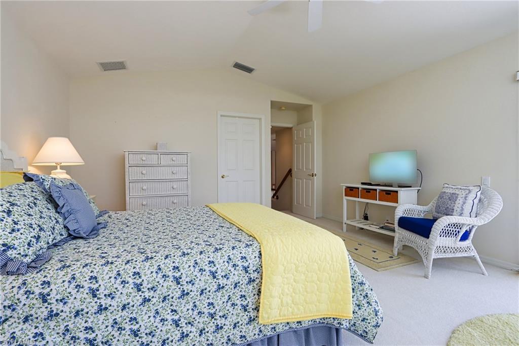 Carpeted bedroom with ceiling fan and vaulted ceiling