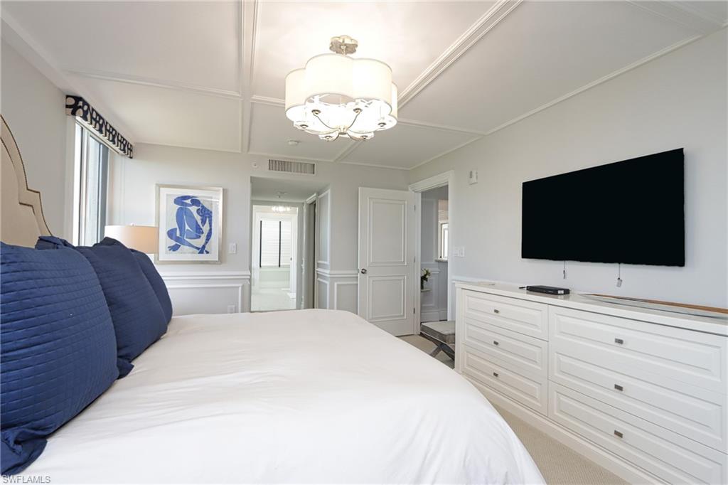 Carpeted bedroom with connected bathroom and a notable chandelier