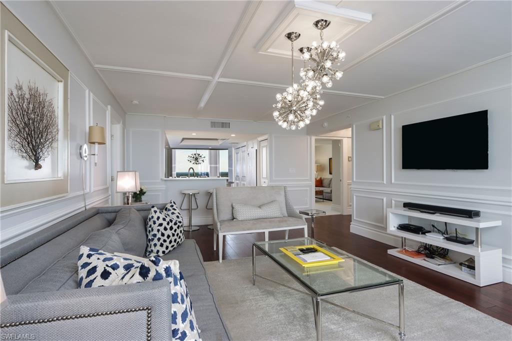 Living room featuring coffered ceiling, hardwood / wood-style flooring, and an inviting chandelier