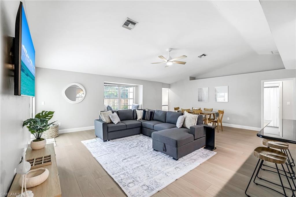 Living room with light wood-style flooring, vaulted ceiling, and a ceiling fan