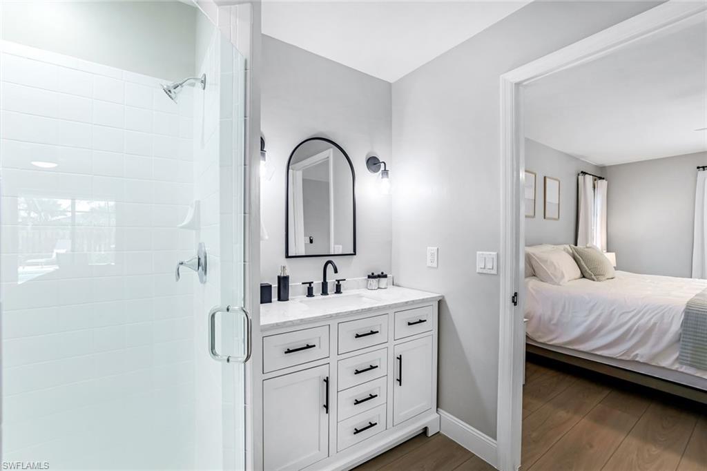 Bathroom with a shower stall, double vanity, dark wood finished floors, and ensuite bathroom