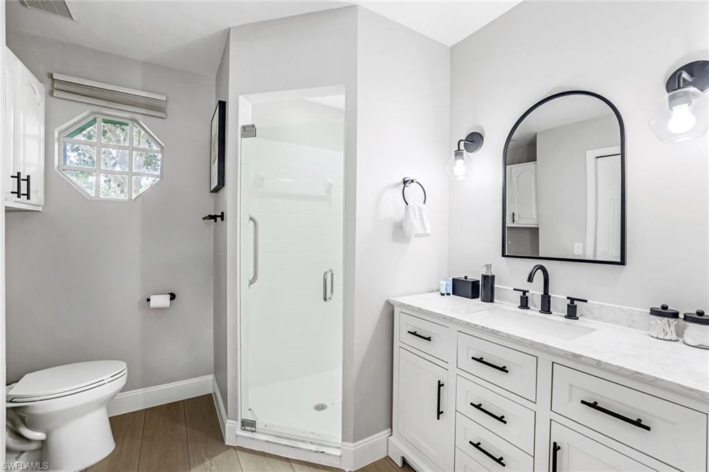 Bathroom with vanity, a shower stall, and light wood finished floors