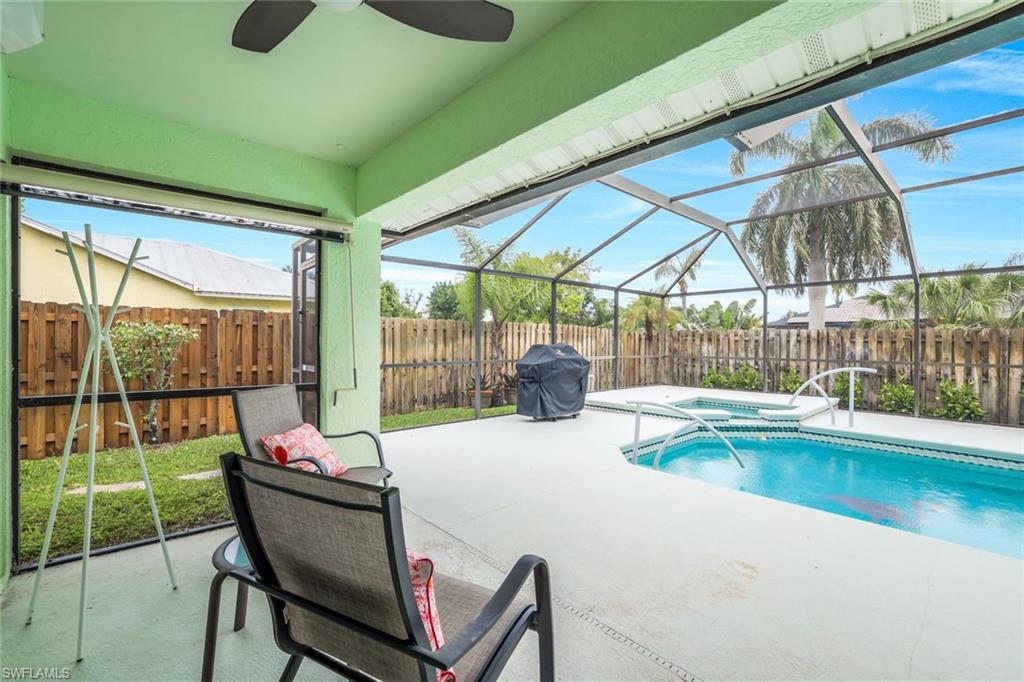 View of swimming pool with glass enclosure, a patio area, a fenced backyard, and grilling area
