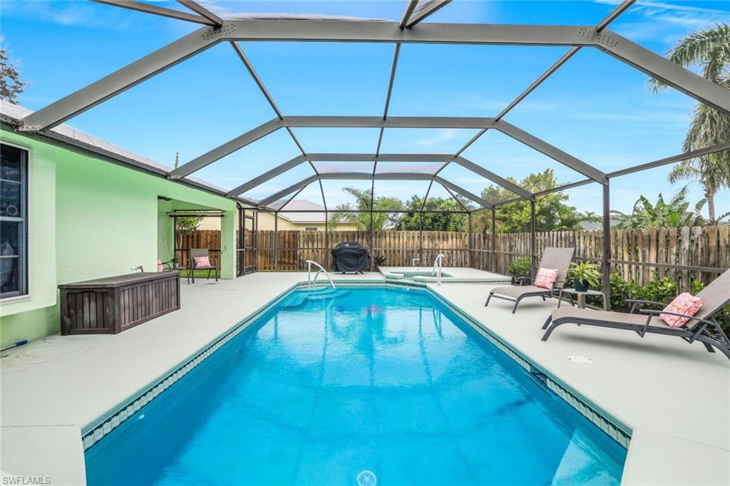 View of swimming pool with an in-ground hot tub, glass enclosure, a sunroom, and a patio area