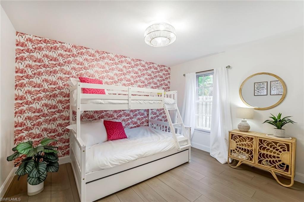 Bedroom featuring light wood-type flooring, wallpapered walls, and an accent wall