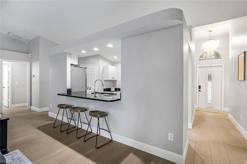Kitchen featuring a peninsula, light wood finished floors, a kitchen breakfast bar, freestanding refrigerator, and recessed lighting