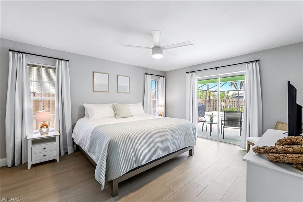 Bedroom featuring multiple windows, access to exterior, and wood finished floors