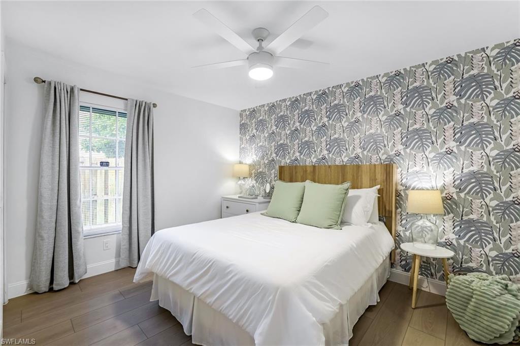 Bedroom with wallpapered walls, dark wood-style flooring, an accent wall, and a ceiling fan