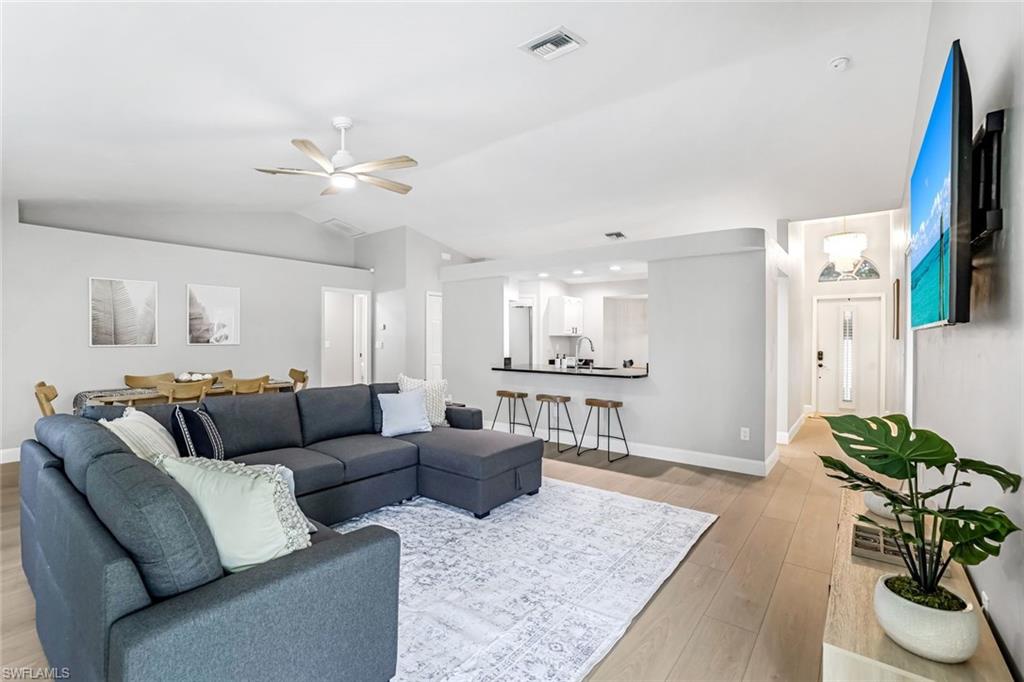 Living area with lofted ceiling, light wood-style flooring, and ceiling fan