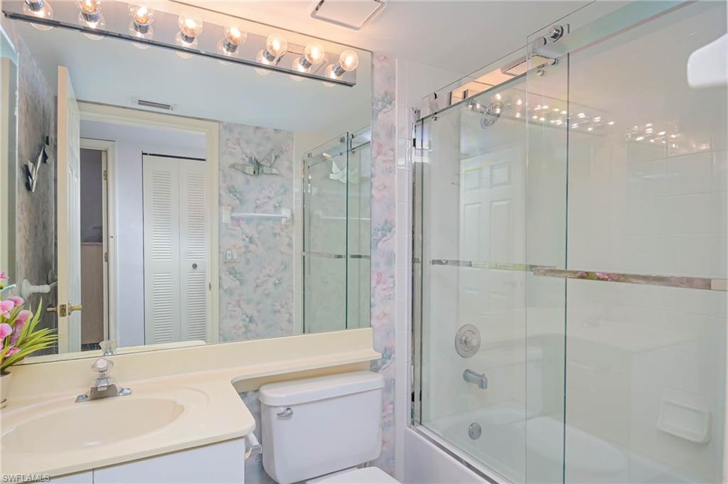 Bathroom with a closet, bath / shower combo with glass door, and vanity