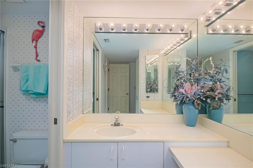 Full bathroom featuring wallpapered walls and vanity