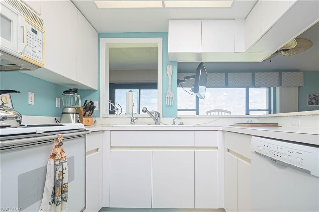 Kitchen featuring white cabinetry, white appliances, light countertops, and modern cabinets