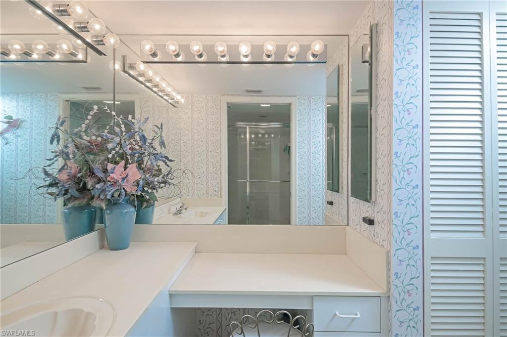 Bathroom with wallpapered walls, a closet, a stall shower, and vanity
