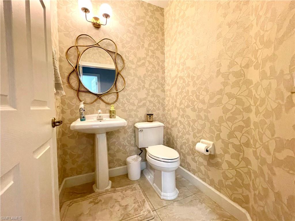 Bathroom with wallpapered walls and tile patterned flooring